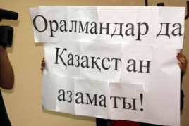 Oralmandar problemasyna arnalǵan jıynǵa qatysýshy ustap turǵan jazý. Almaty, 4 qazan 2011 jyl. (Kórneki sýret)