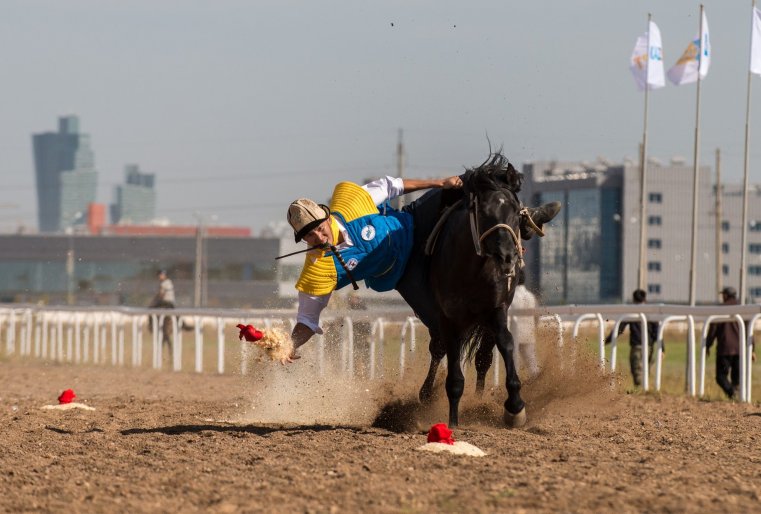 Наездник, сидя на лошади, должен наклониться вниз и подобрать завернутые в платок деньги.