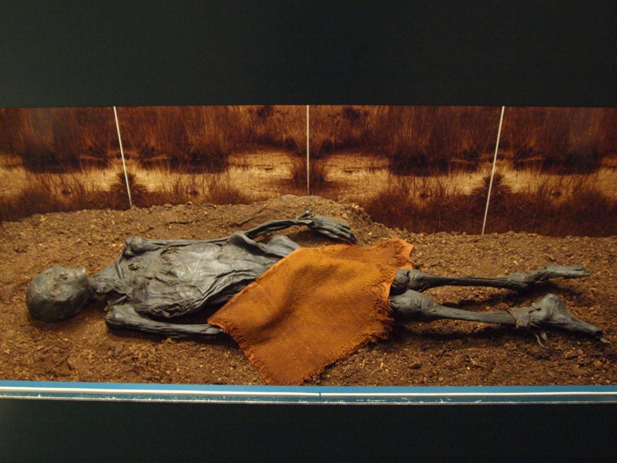 Ер адам суға түсуге арналған киімдерін шешіп, жұлқылайды